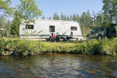 Family relaxing in front of camper trailer