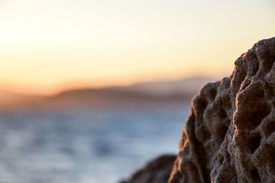 Close-up of cliff on sea at sunset