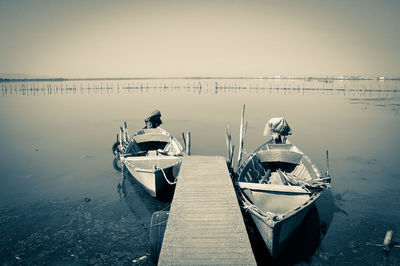 Boats moored at harbor against clear sky