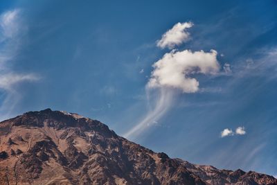 Low angle view of mountain and clouds against sky