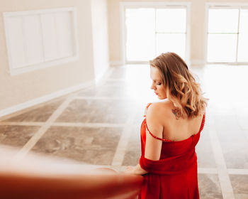 Beautiful woman standing by window at home