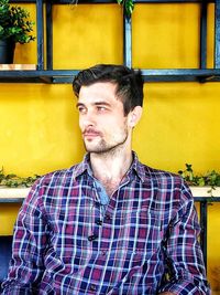 Thoughtful young man against yellow wall