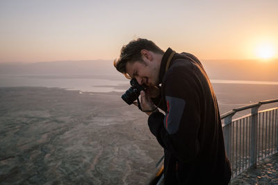 Man photographing at observation point during sunset