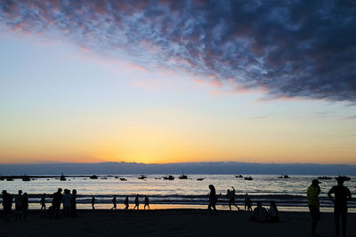 Silhouette people on beach against sky during sunset