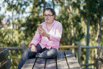 Man looking away while sitting on tree