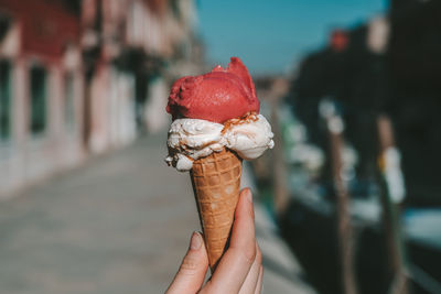 Cropped hand holding ice cream cone in city