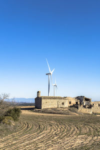 Wind turbines in between agricultural fields and an abandoned old town in catalonia spain