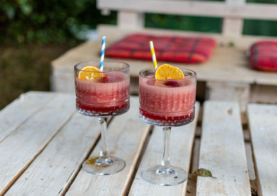 Close-up of two red cocktails in vintage glasses on white pallet table in bar