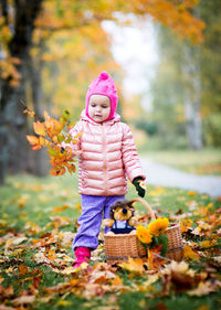 Full length of cute girl with autumn leaves