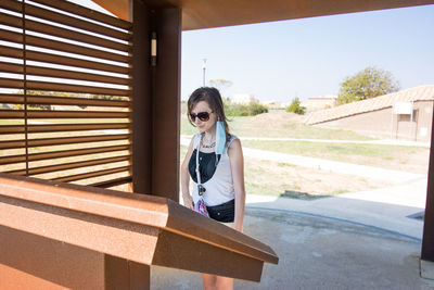 Girl wearing sunglasses standing against built structure