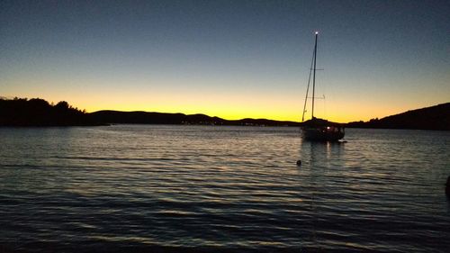 Sailboat sailing in sea at sunset