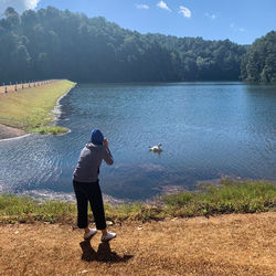 Rear view of woman standing by lake