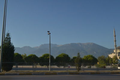 Street by mountains against clear blue sky