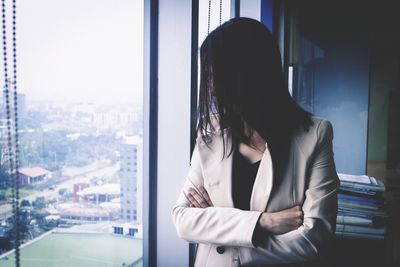 Woman standing by window in city