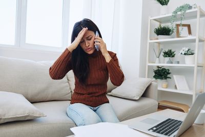 Young woman using laptop while sitting on sofa at home