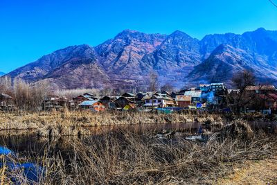 Houses on field against clear blue sky