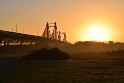 View of suspension bridge over river at sunset