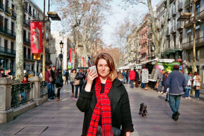 Portrait of woman holding disposable glass on street in city