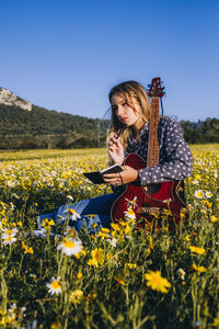 Young woman with yellow flowers on field against sky