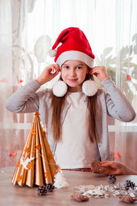 Christmas handmade. the girl tries on christmas tree decorations as earrings. vertical view