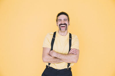 Happy man standing against yellow background