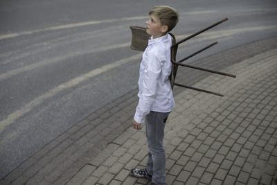 Young boy carrying a chair