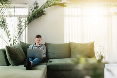 Man using mobile phone while sitting on sofa at home