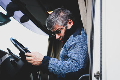 Close-up of man using mobile phone in bus