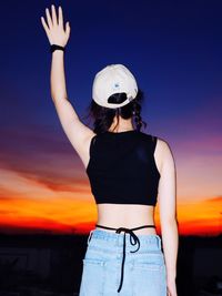 Rear view of woman standing against sky during sunset