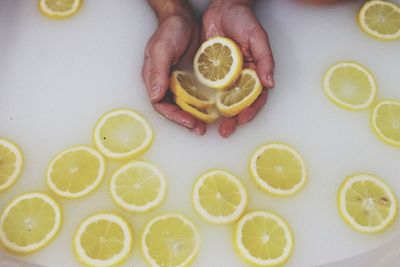 High angle view of hand holding lemon in container 