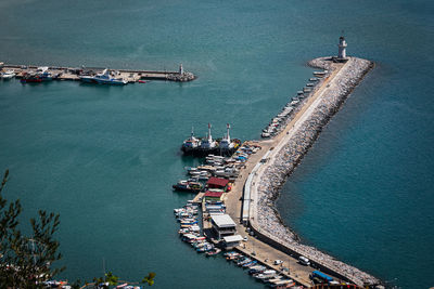 Top view of a pier with a beautiful white lighthouse and a pier with many boats and yachts