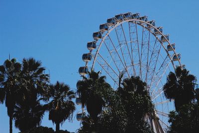 Low angle view of ferris wheel against blue sky