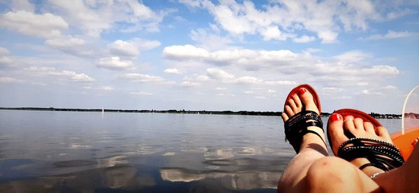 Low section of woman standing in water against sky