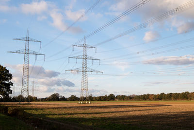 Electricity pylon on field against sky