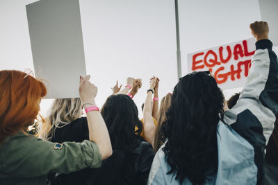 Rear view of women protesting for equal rights against sky in summer