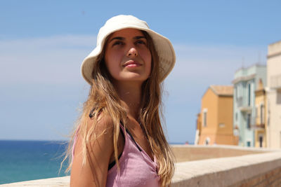 Portrait of young woman looking away against sky