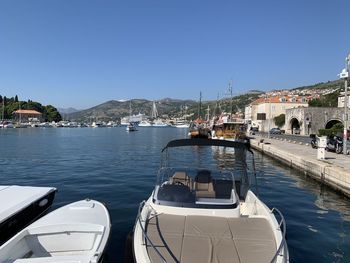 Sailboats moored in sea against clear blue sky