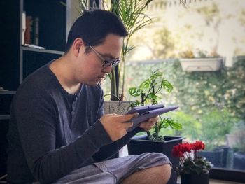 Side view of young man sitting on plant