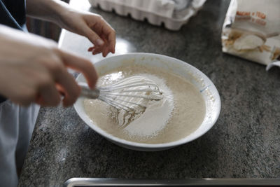 Anonymous person mixing flour into batter while cooking pastry at home person