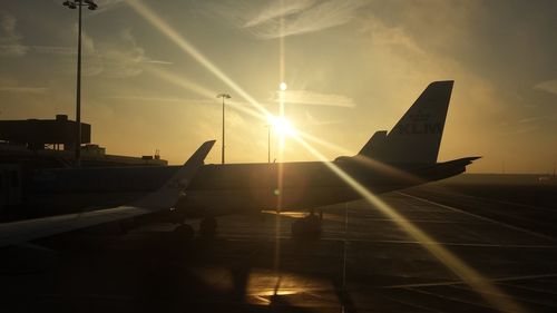 Airplane wing against sky during sunset