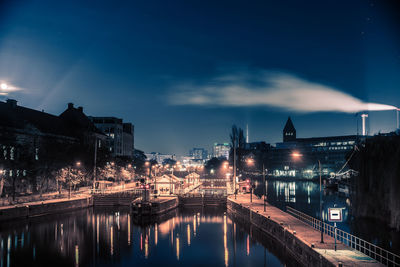 Illuminated bridge over river against sky in city at night