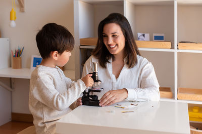 Mother assisting son in puzzle sitting at home