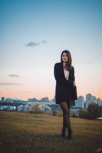 Portrait of woman standing on field against sky during sunset