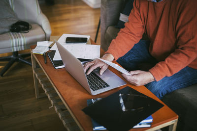 Midsection of gay man calculating financial bills at home