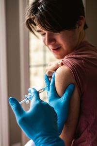 Close up of teen boy getting vaccinated by doctor holding a needle.