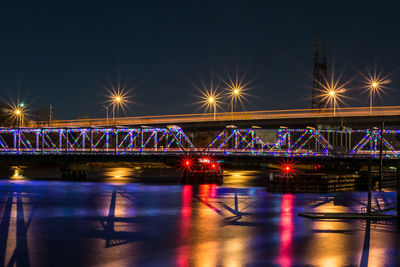 Light trails on bridge against sky at night