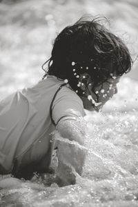 Rear view of girl with arms raised in water