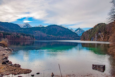 Scenic view of lake by mountains against sky in alpsee, bavaria.