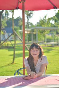 Side view of young woman sitting on field