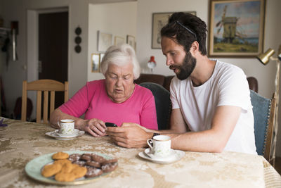 Man showing senior woman cell phone